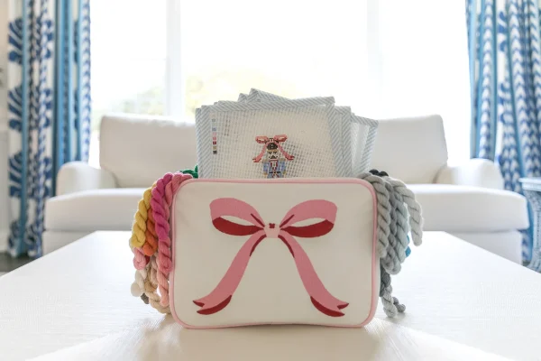 Box of needlepoint works with pink bowtie on front in white living room